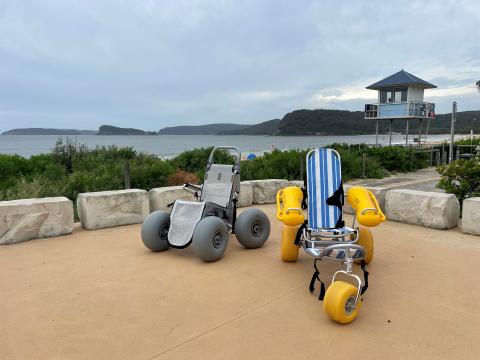 two types of beach wheelchairs on concreate platform with beach in background