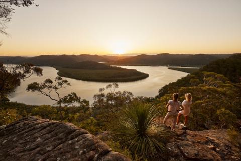 Central Coast tourism women standing high on a bush rock overlooking expanse of bush and river