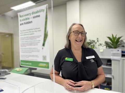 Council Customer Service Officer wearing the Hidden Disabilities Sunflower merchandise Council Customer Service Officer working at front desk wearing Hidden Disability Sunflower merchandise