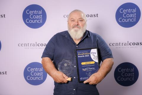 The Bikers Hand Inc, represented by Tony Davis (Community Group Award) man standing in front of screen holding an award
