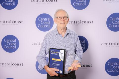 Paul Mikkelsen (Volunteer Award, joint winner) man standing in front of screen holding an award